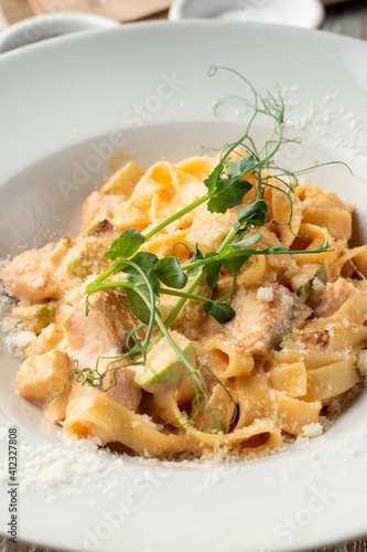 Salmon pasta with capers and creamy sauce in white wide dish