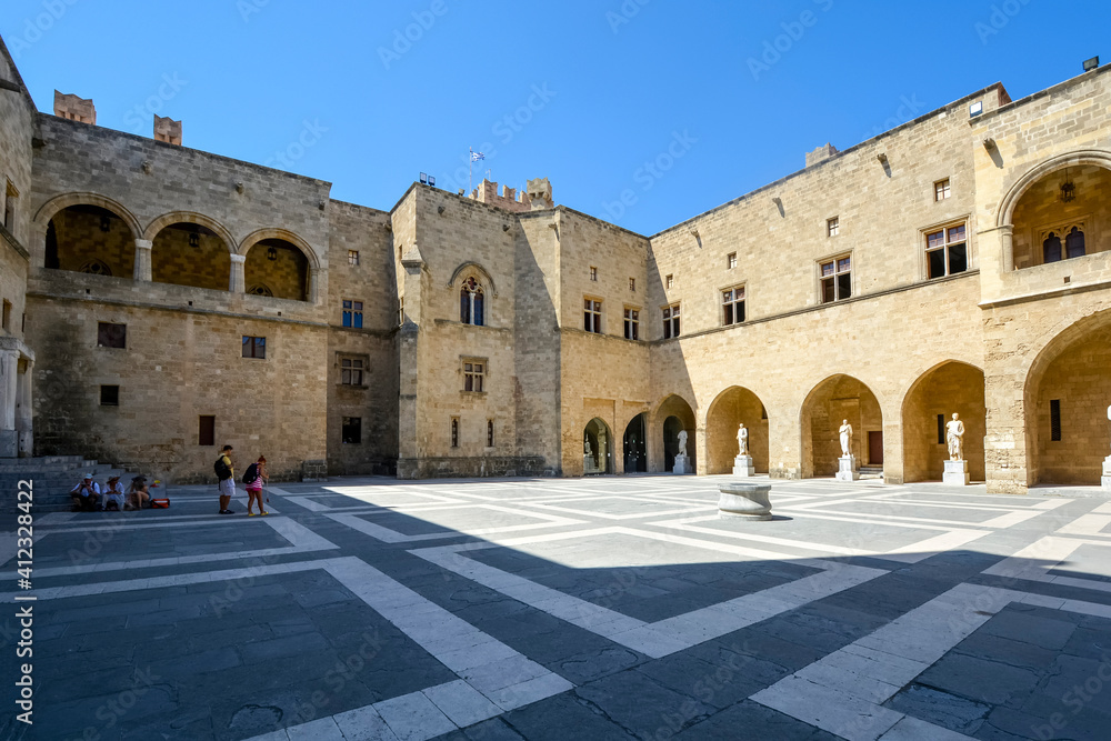 Unidentifiable tourists visit the interior courtyard of the Palace of the Grand Master of the Knights of Rhodes on the island of Rhodes, Greece.