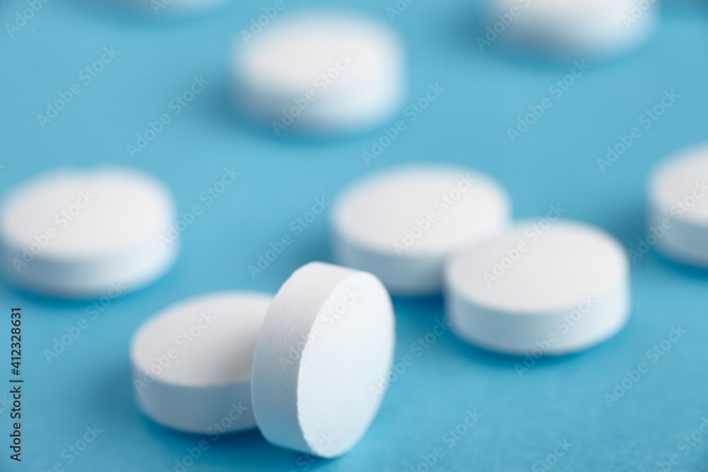 Closeup of white pills on a blue background. Heap of pills - medical background