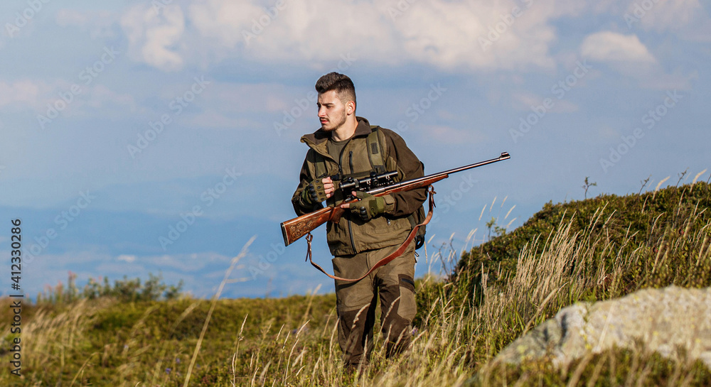 Hunter is aiming. The man is on the hunt. Hunt hunting rifle. Hunter with hunting gun and hunting form to hunt sky background Hunter is aiming. The man is on the hunt. Hunt hunting rifle. Hunter with hunting gun and hunting form to hunt sky background