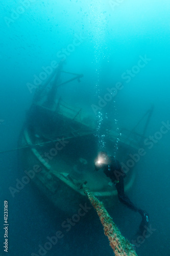 Scuba diver exploring the shipwreck deep under the sea photo