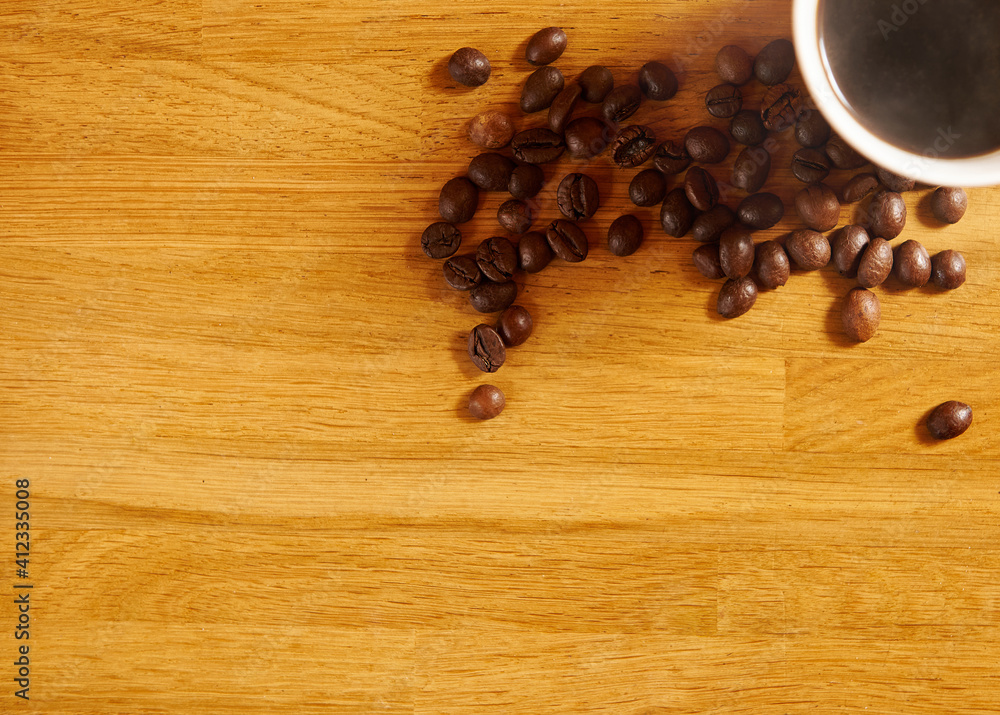 Flat lay. Scattered roasted coffee beans next to a takeaway cup of aromatic black coffee on a wooden table. Top view with copy space Flat lay. Scattered roasted coffee beans next to a takeaway cup of aromatic black coffee on a wooden table. Top view with copy space