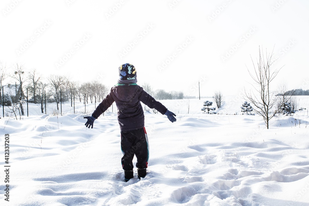 Caucasian boy child playing in the snow during cold and snowy winter, healthy lifestyle and physical activity od children to strengthen immunity