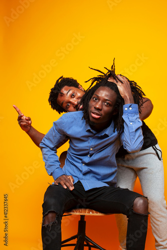 two african american guys posing cheerful together on yellow background, lifestyle people concept © iordani