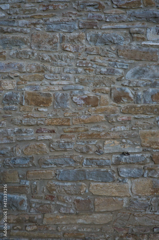 Stone wall of natural stones in different sizes; Rustic stone veneer in shades of brown and beige