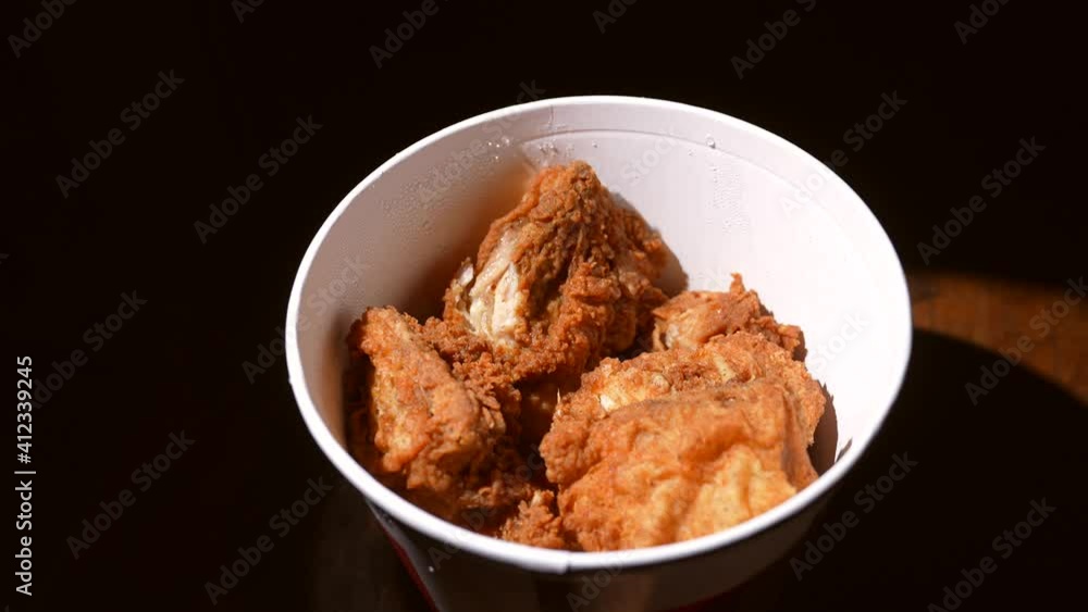 This video shows a close up, top view of an anonymous hand grabbing a fresh piece of fried chicken from a fast food container. This video shows a close up, top view of an anonymous hand grabbing a fresh piece of fried chicken from a fast food container.