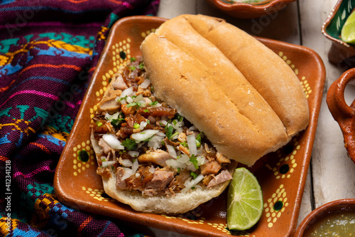 Confit pork sandwich called Torta de carnitas on white background. Mexican food photo