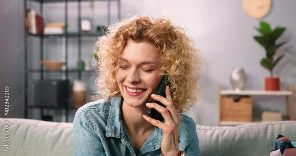 Happy beautiful blonde curly multiracial woman involved in pleasant smartphone call conversation with friends while sharing and discussing life news. Smiling female client calling operator Happy beautiful blonde curly multiracial woman involved in pleasant smartphone call conversation with friends while sharing and discussing life news. Smiling female client calling operator