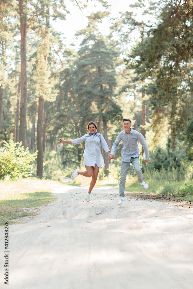 Fototapeta premium young couple in love having fun and enjoying the beautiful summer nature. woman and man, wearing in denim outfit are having date outdoors in the park. Romantic relationship. valentines day