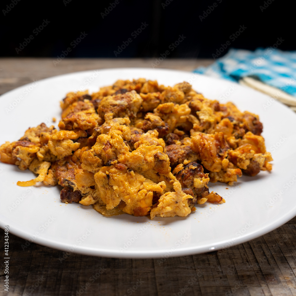 Scrambled eggs with chorizo for breakfast on wooden background. Mexican food Scrambled eggs with chorizo for breakfast on wooden background. Mexican food