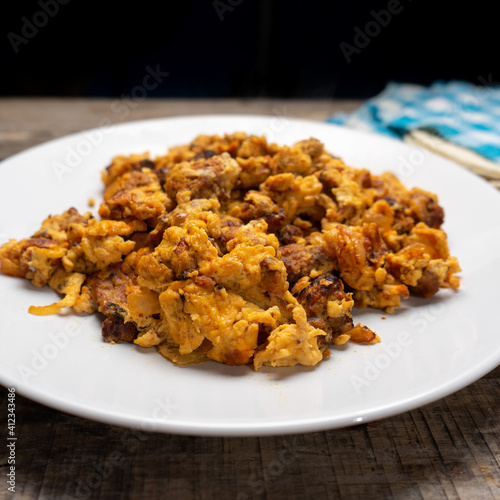 Scrambled eggs with chorizo for breakfast on wooden background. Mexican  food