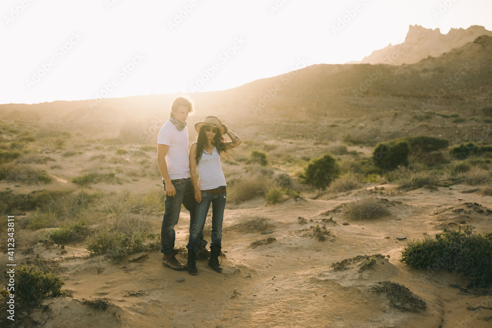 young couple in cowboy style in the desert at sunset young couple in cowboy style in the desert at sunset