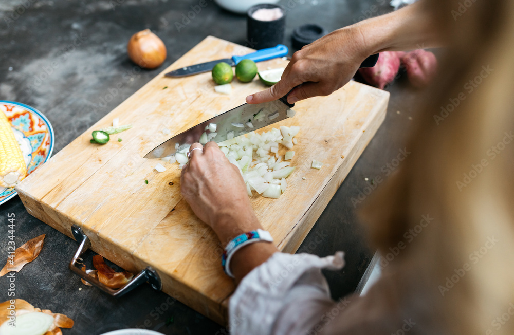 young woman prepares and chops vegetables on cutting board in kitchen young woman prepares and chops vegetables on cutting board in kitchen