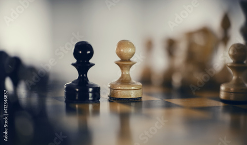 Two pawns - black and white. Wooden chess pieces on the chessboard.