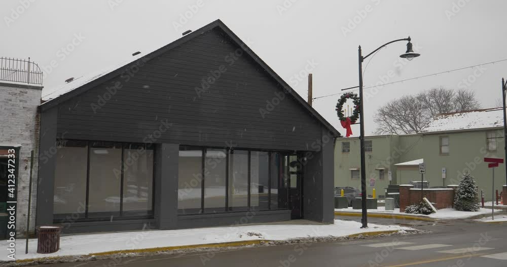 A daytime winter establishing shot of an unbranded storefront in the business district of a small town. Blank marquee for customization. A daytime winter establishing shot of an unbranded storefront in the business district of a small town. Blank marquee for customization.