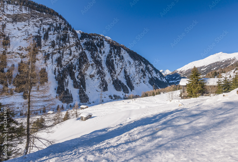 Winter landscape with valley in snowy mountains. Sunny winter day in Alps. Christmas holiday and winter vacations concept.