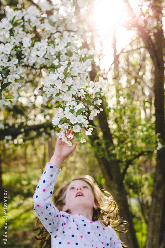 Girl leaping and reaching for a flowering tree Girl leaping and reaching for a flowering tree