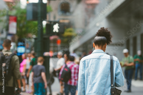 Woman walking through crowded city street with headphones