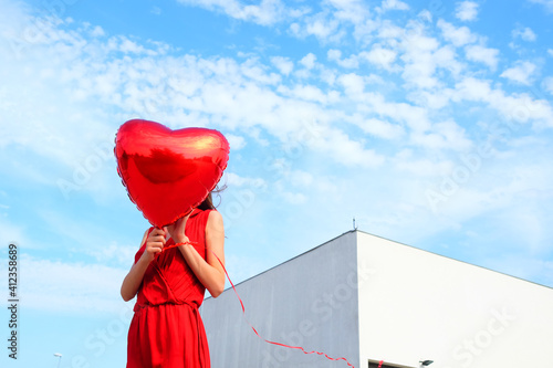 Anonymous female model with red heart ballon outside on a sunny day photo