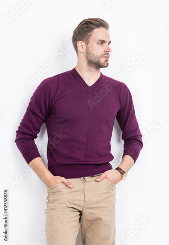Attractive guy with serious look pose keeping hands in pants pockets in casual fashion style, model © Olena