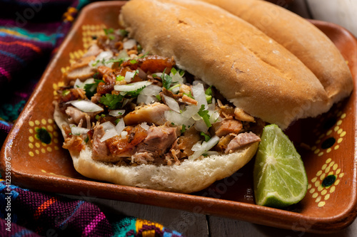 Confit pork sandwich called Torta de carnitas on white background. Mexican food photo