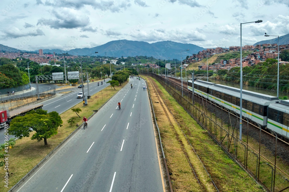 Autopista a las afueras de la ciudad. Ciclistas que compiten en la carretera. Avenida con arboles. Montañas al fondo. Camino de curvas. Carretera a las afueras de Medellín, Colombia