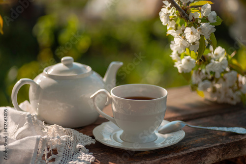 Tea set, cherry blossom branches, wooden table. Outdoor breakfast, picnic, brunch, spring mood. Soft focus