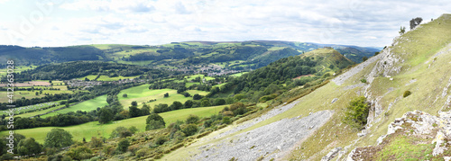 Panoramic view of the Vale of Llangollen, with the town, ruins of Castell Dinas Bran, camping sites and fields following the River Dee through the valley below the Welsh hills all within the photo. 
