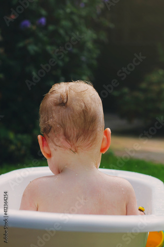 A baby girl is taking a bath outside in the warm summer air photo