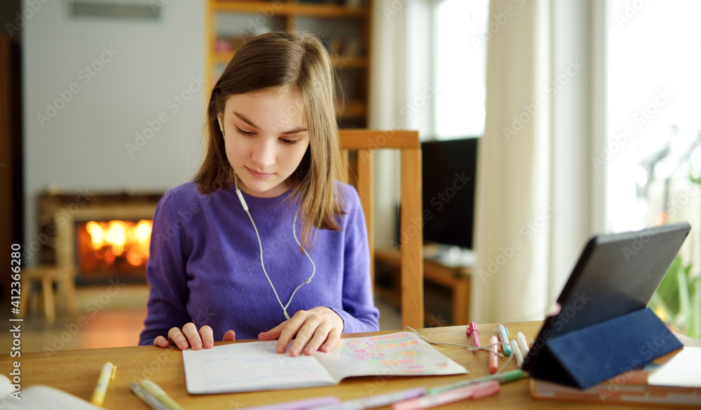 Preteen schoolgirl doing her homework with digital tablet at home. Child using gadgets to study. Education and distance learning for kids. Homeschooling during quarantine. Preteen schoolgirl doing her homework with digital tablet at home. Child using gadgets to study. Education and distance learning for kids. Homeschooling during quarantine.