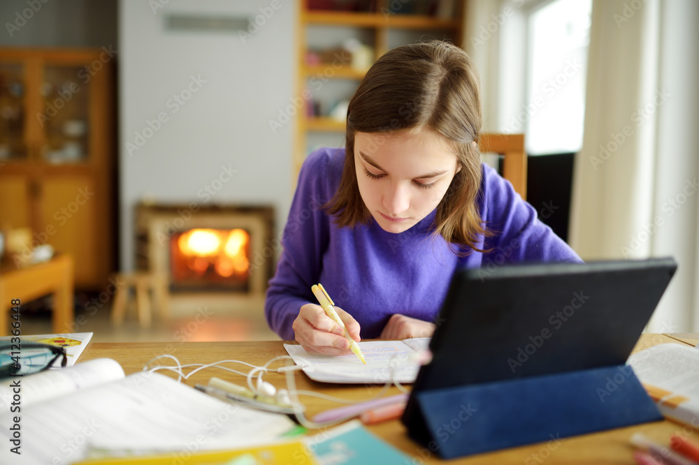 Preteen schoolgirl doing her homework with digital tablet at home. Child using gadgets to study. Education and distance learning for kids. Homeschooling during quarantine. Preteen schoolgirl doing her homework with digital tablet at home. Child using gadgets to study. Education and distance learning for kids. Homeschooling during quarantine.