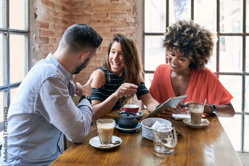 Portrait of laughing friends browsing tablet in cafe with drinks on table. Portrait of laughing friends browsing tablet in cafe with drinks on table.