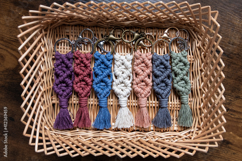 Seven (7) cotton macrame keychains are displayed in a wicker basket. photo