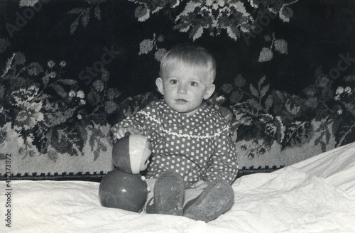 Vintage monochrome photo of little lovely girl sitting on the bed
