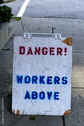 View of sign "Danger! Workers above" on sidewalk in Vancouver, Canada.