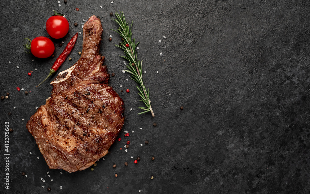 grilled cowboy steak with spices on a knife on a stone background with copy space for your text