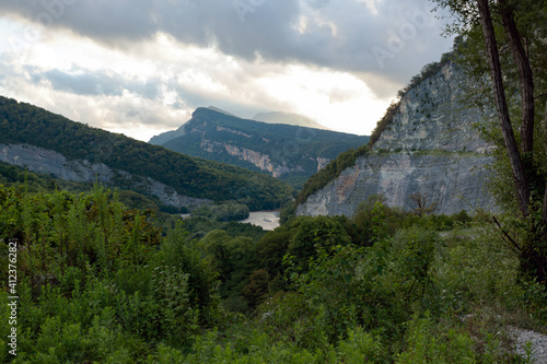 Mountain gorge with river below against cloudy cloudy sky
