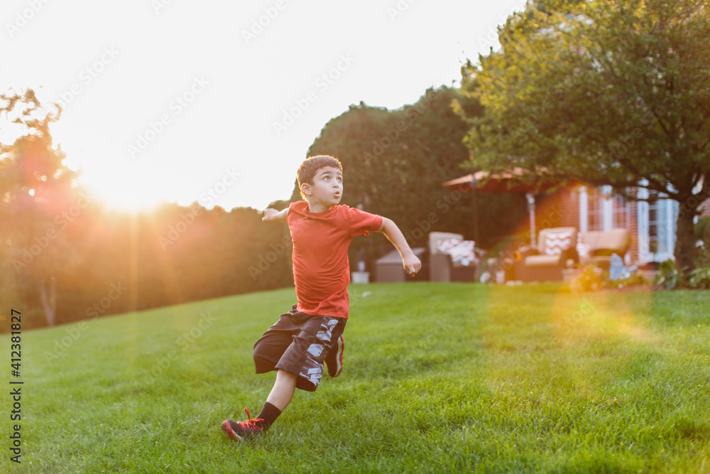 Young boy playing football in a backyard Young boy playing football in a backyard