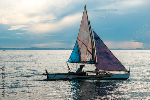 Small home made sail cruising during a sunset