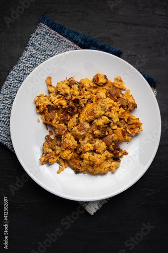 Scrambled eggs with chorizo for breakfast on dark background. Mexican food