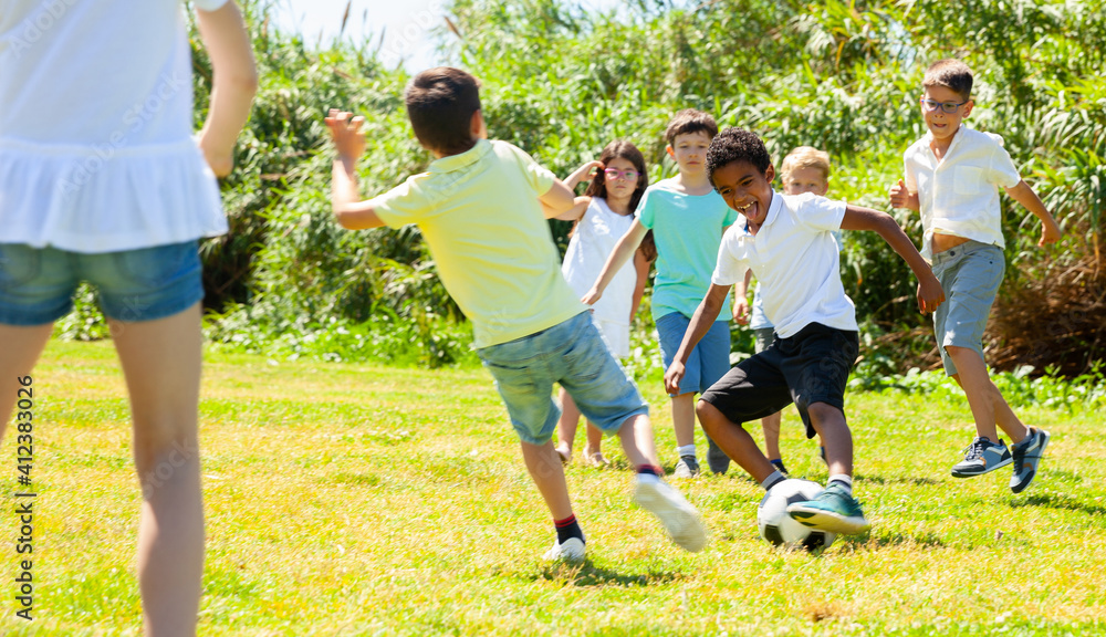 Obraz premium Group of happy kids are running and playing football in park at summer day