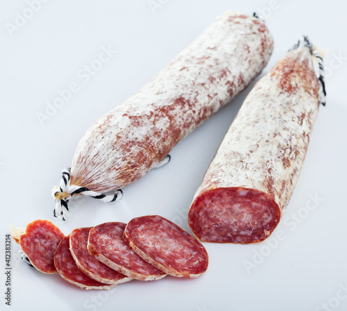Catalan sort of popular Spanish Longaniza sausage from minced pork with cut slices on white surface