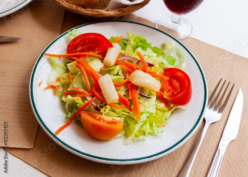 Mediterranean vegeterian salad served with carrot and onion on wooden table
