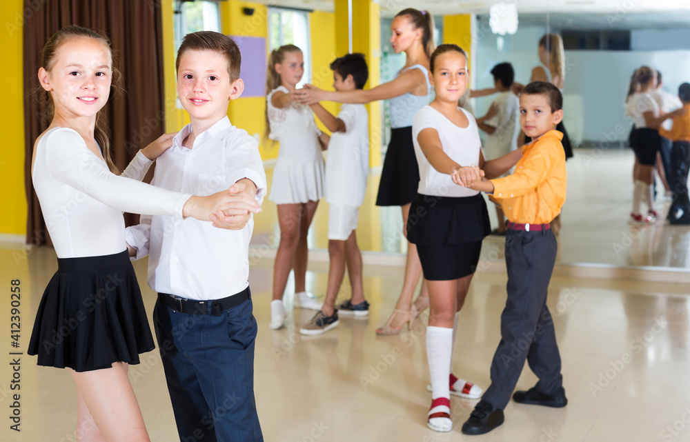 Pairs of children are dancing tango in class.v