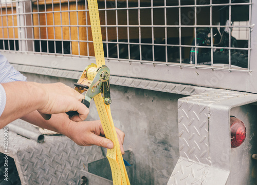 a man tightens a strap to secure furniture on a trailer photo