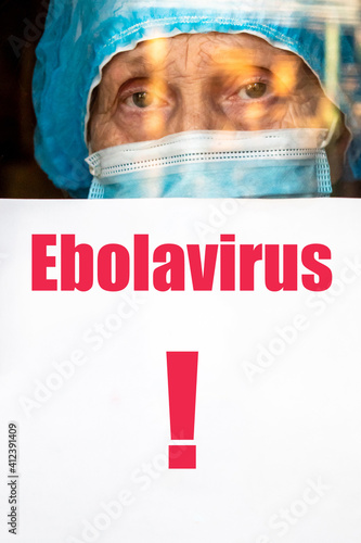 Art noise. Elderly woman doctor in uniform shows a paper with inscription ebola virus through the window. New case of ebolavirus infection was recorded in the Congo. Possibility of a new epidemic. photo