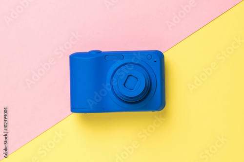 Top view of a blue camera on a yellow and pink background.