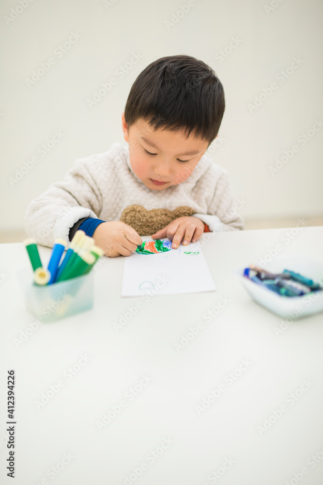 Chinese Kid Coloring a Paper at the Table Chinese Kid Coloring a Paper at the Table