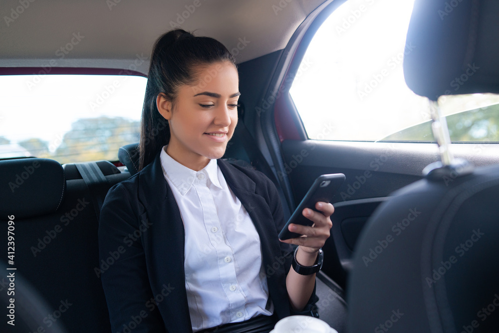 Businesswoman using mobile phone in car.