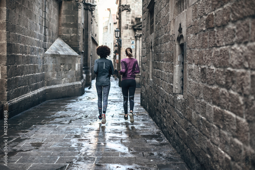 Back view of two young women running on Barcelona streets. Back view of two young women running on Barcelona streets.